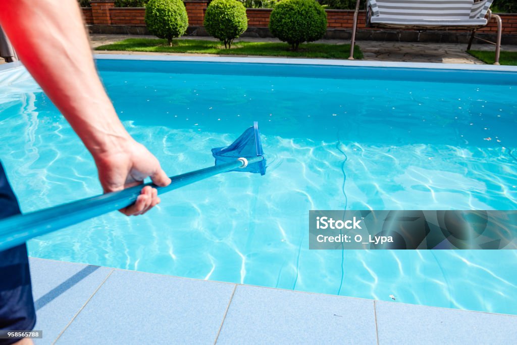 Male hand hold pool net cleaner Worker make maintenance of swimming pool. Male hand hold pool net cleaner. Swimming Pool Stock Photo