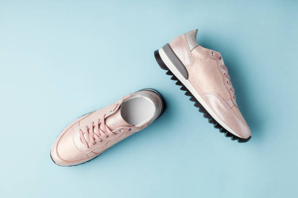 istock Pastel pink female sneakers on blue background. 958565996