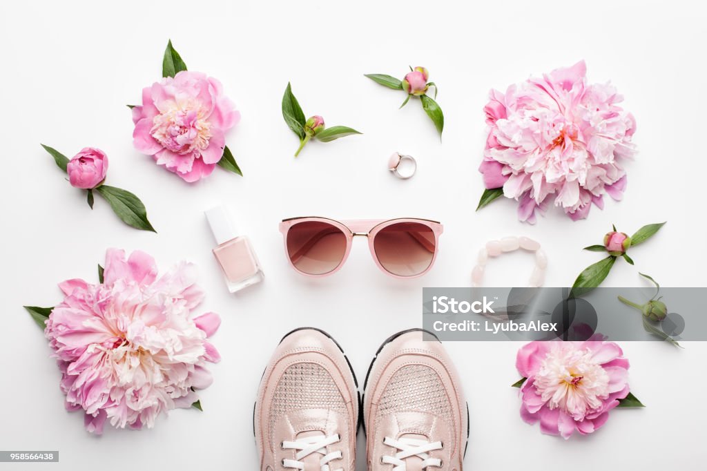 Flat lay pink feminine accessories and peony flowers on white. Flat lay pink feminine accessories and peony flowers on white background. Flat Lay Stock Photo
