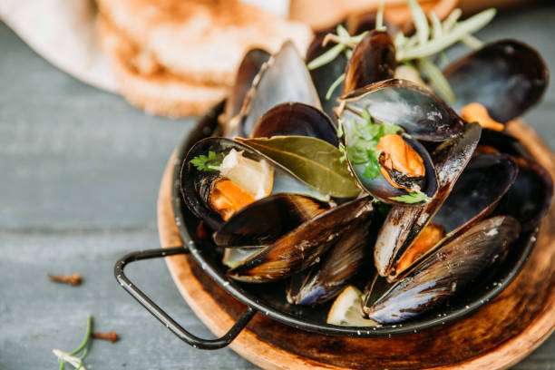 istock Shellfish Mussels with lemon and herbs on wooden background. Top view. 958569014
