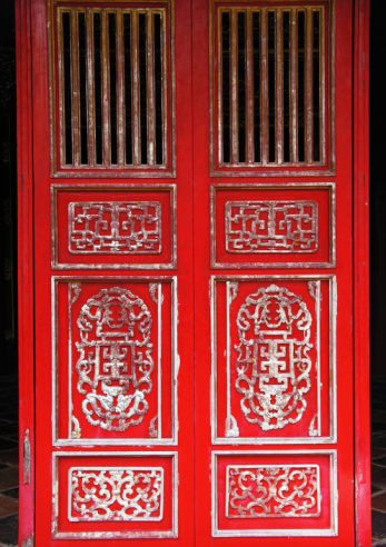 art nouveau design door, with colored glass, decorative figures engraved on wood and beautiful ornaments like the wooden sculpture of the head of a woman - entrance of an antiquarian store