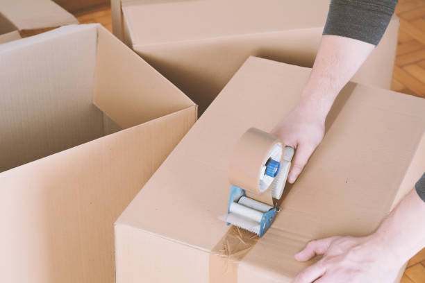 istock Man sealing a shipping cardboard box 958584024