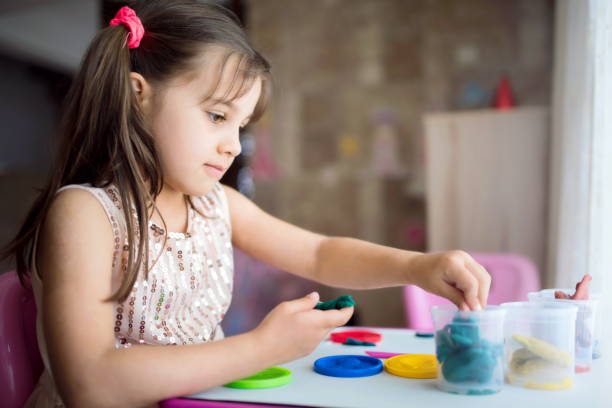 istock Little Girl Playing With Putty At Home 958597434