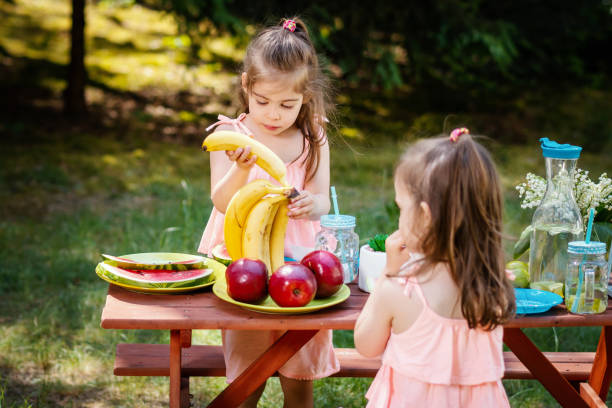 istock two girls eat fruit at a summer picnic 958599806