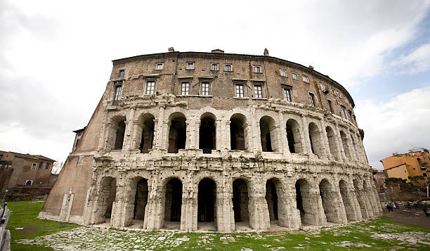 This aerial shot features the ancient Teatro di Marcello in Rome, an open-air theatre built in the late Roman Republic era, resembling a smaller version of the Colosseum. Located near the Tiber River, the theatre is surrounded by archaeological ruins and historic buildings. In the background, the Great Synagogue of Rome stands prominently with its distinctive dome, marking the city's Jewish heritage. The juxtaposition of classical architecture with religious monuments highlights the layered cultural history of Rome, offering rich visual storytelling for themes related to archaeology, history, and heritage tourism.
