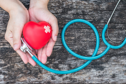 Negocio seguro médico profesional de la salud y el concepto de día de salud mundo corazón con corazón rojo en apoyo de las manos de la mujer con estetoscopio del doctor photo