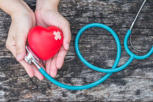 attività di assicurazione medica sanitaria e concetto di giornata mondiale della salute del cuore con cuore rosso sulle mani della donna supporto con stetoscopio del medico - settimana foto e immagini stock