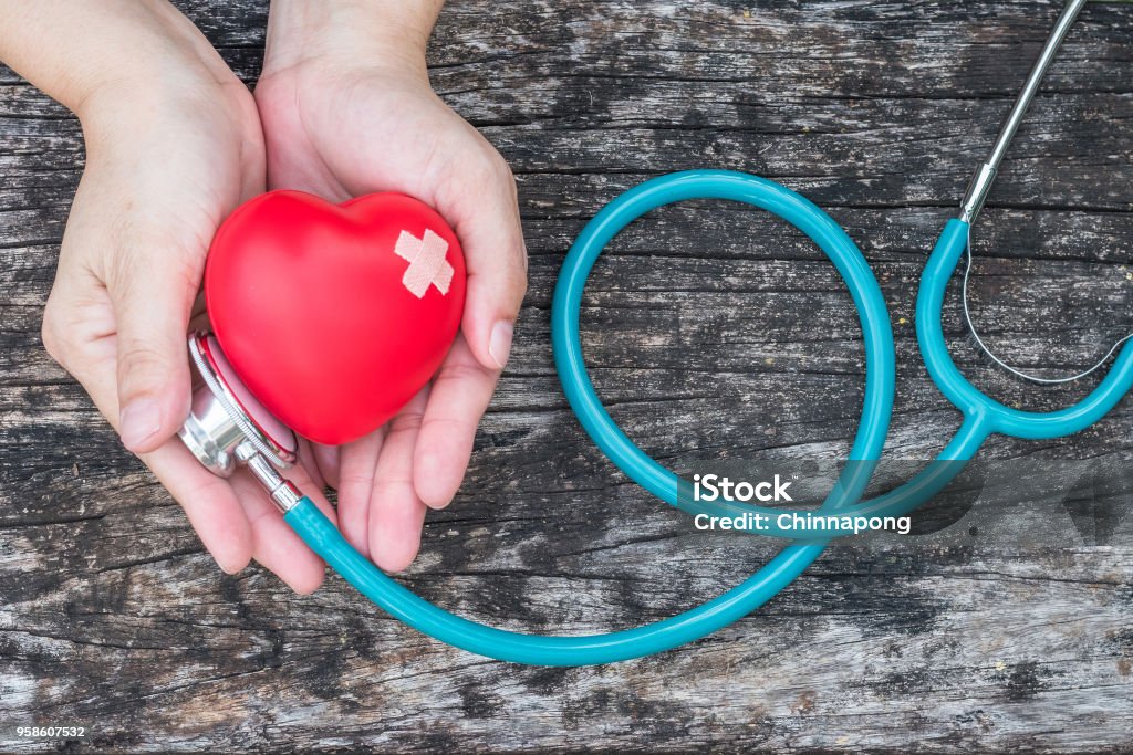 Healthcare medical insurance business and world heart health day concept with red heart on woman's hands support with doctor's stethoscope Nurse Stock Photo