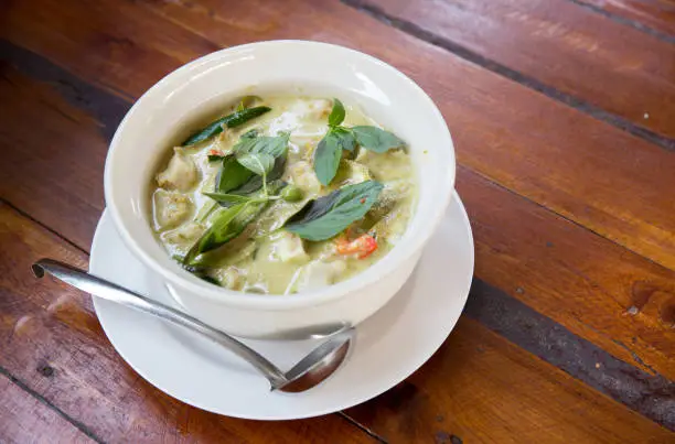 Photo of Thai chicken green curry with old wooden background.closeup green curry with chicken