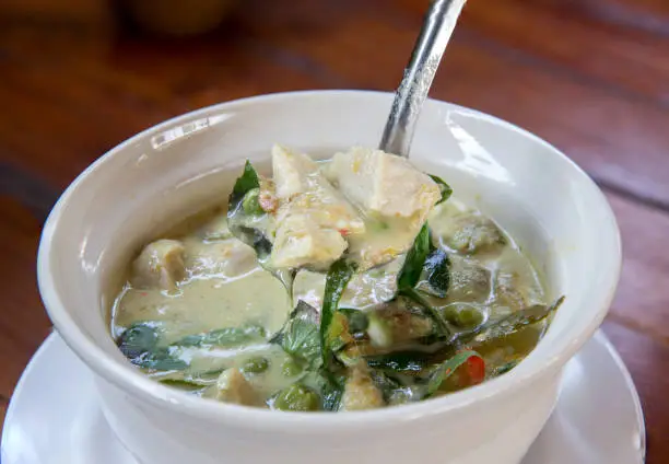 Photo of Thai chicken green curry with old wooden background.closeup green curry with chicken
