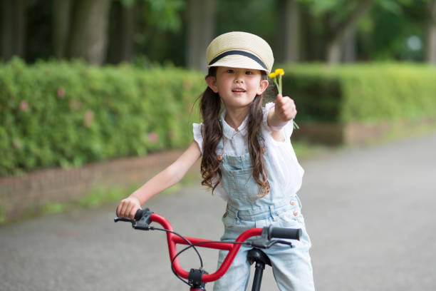 Girl hold out a flower ride a bicycle