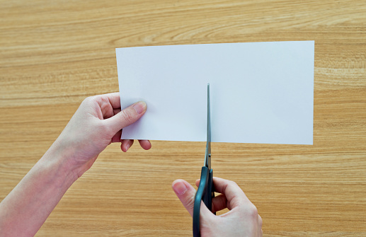 Woman hands using scissors cutting a blank paper