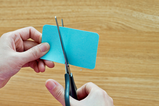 Woman hands using scissors cutting a blue paper