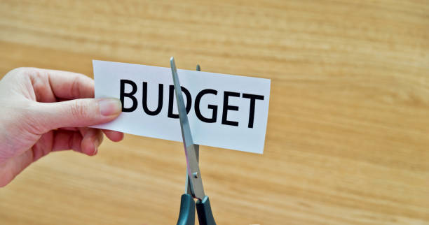 istock Human hand cutting the budget word 958635478