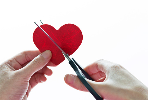 Human hand holding Scissors cutting heart shape