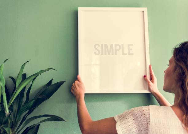 Girl hanging a frame on a green wall
