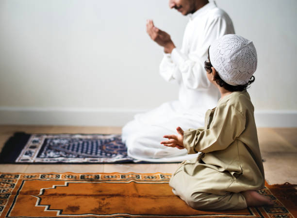 petit garçon prier aux côtés de son père pendant le ramadan - islam photos et images de collection
