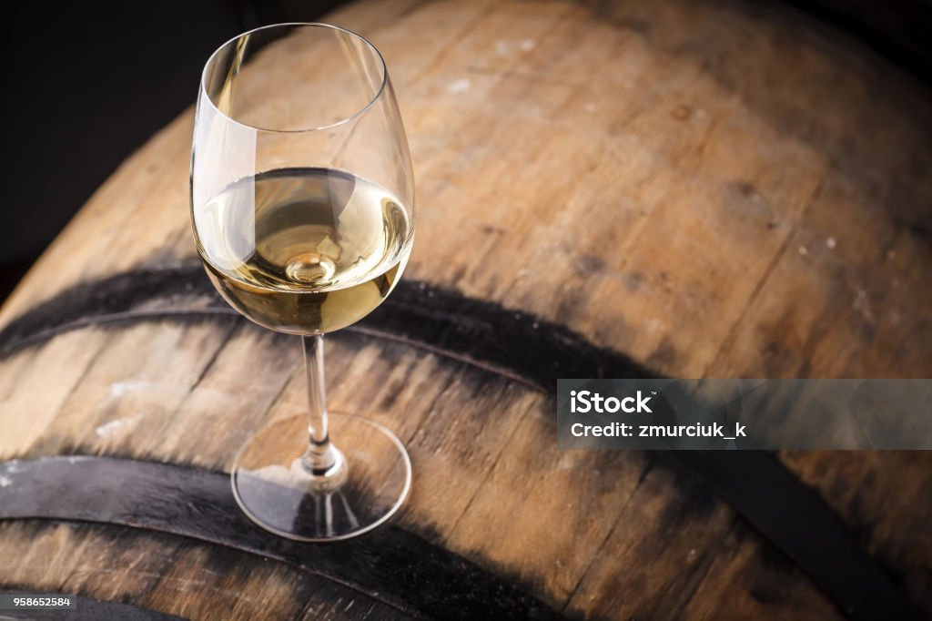 White wine on a barrel Glass of white wine standing on an oak barrel in a cellar White Wine Stock Photo