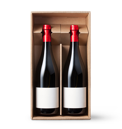 Two bottles of red wine in cardboard box on white background.