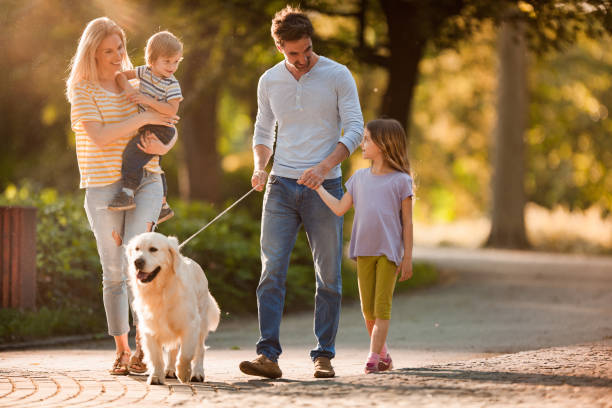 Happy family talking while walking with a dog in spring day.