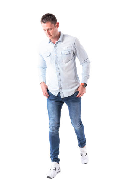 istock Young handsome man walking with hands in pockets and looking down 958663876