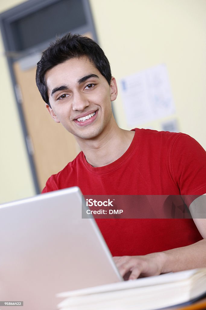 Felice studente maschio, lavorando su un computer portatile in aula - Foto stock royalty-free di 16-17 anni