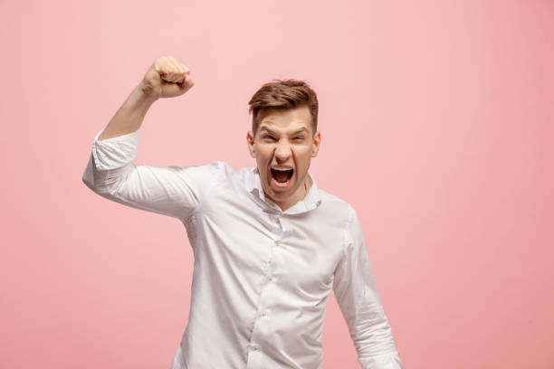 istock The young emotional angry man screaming on pink studio background 958666456