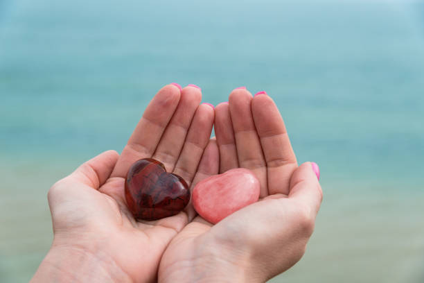 istock Two stone hearts on woman's hands against blue ocean 958666644