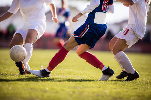 Unrecognizable soccer player running with ball on a match while avoiding her opponent. Unrecognizable female soccer players playing a match on a field. offense sporting position photos stock pictures, royalty-free photos & images