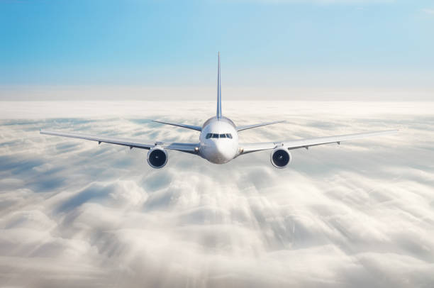 istock Passenger airplane flying at flight level high in the sky above overcast clouds and blue sky. View directly in front, exactly. 958666916