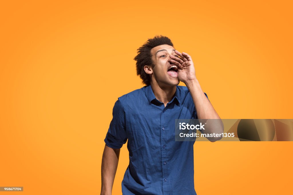 Isolées sur les blue jeune homme casual criant au studio - Photo de Crier libre de droits