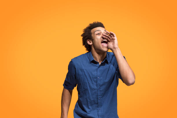 Isolated on blue young casual man shouting at studio Young afro man shouting. Crying emotional man screaming on blue studio background. Male half-length profile portrait. Human emotions, facial expression concept. Trendy colors. shouting stock pictures, royalty-free photos & images