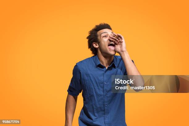 Isolated On Blue Young Casual Man Shouting At Studio Stock Photo - Download Image Now