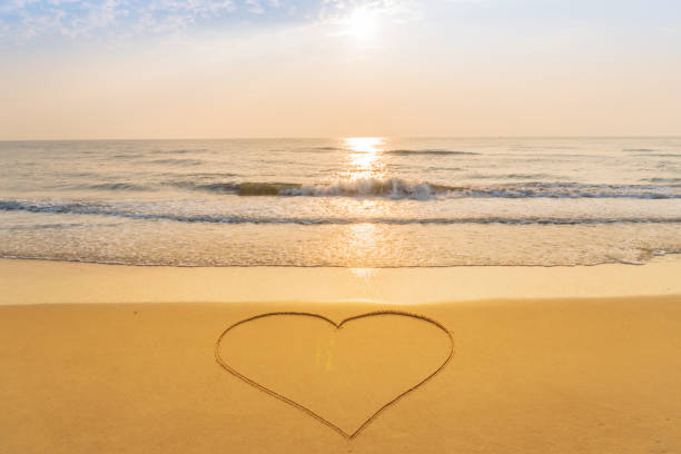 istock Heart drawn on the sand beach background at sunrise 958671990