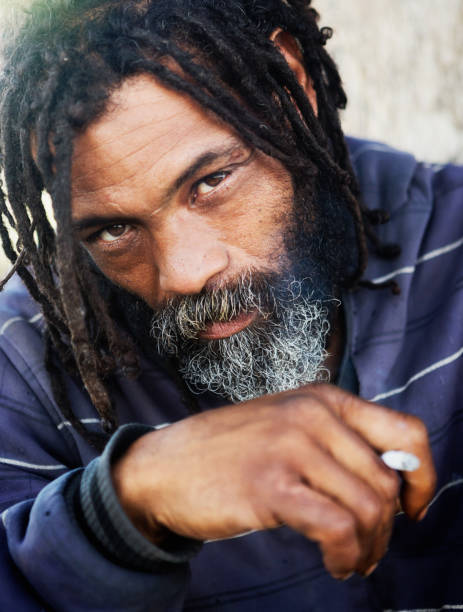 istock Dreadlocked man looks wary as he smokes a cigarette 958672598