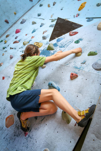 adolescente formação escalada na parede de escalada indoor - climbing wall rock climbing holding reaching - fotografias e filmes do acervo