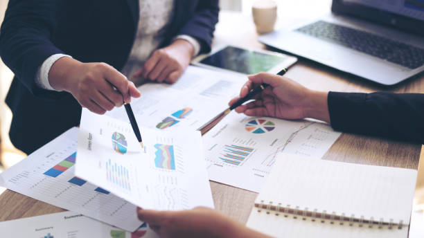 istock financial Image of two  business people pointing at business document presentation summary report , during discussion at meeting , Notebook on wood table 958676666