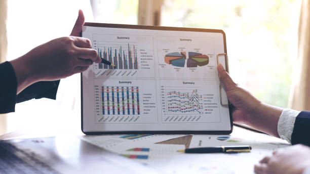 istock financial Image of two  business people pointing at business document presentation summary report , during discussion at meeting , Notebook on wood table 958676676