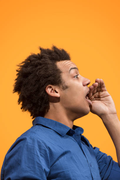 istock Isolated on orange young casual man shouting at studio 958676802