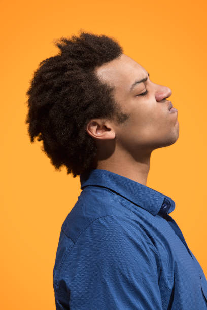 istock The young emotional angry man screaming on orange studio background 958677026