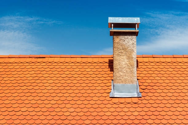 Modern roof with chimney. Orange ceramic tile, shingle. Blue sky on the background stock photo