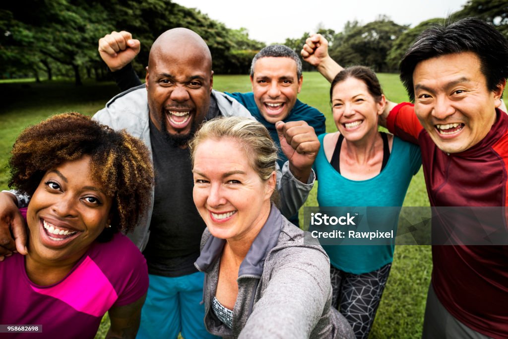 Gruppo di allegri amici diversi nel parco - Foto stock royalty-free di Gruppo di persone