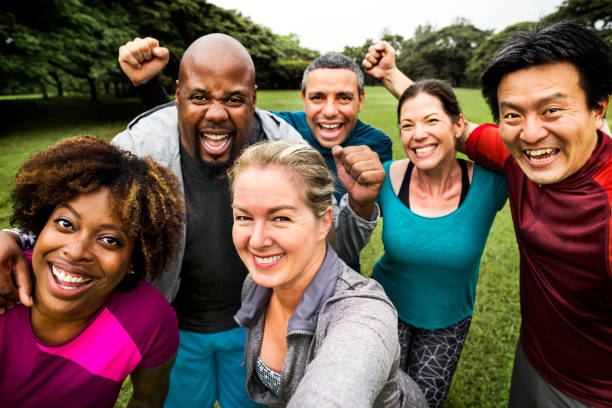 grupa wesołych różnorodnych przyjaciół w parku - exercising group of people outdoors sport zdjęcia i obrazy z banku zdjęć