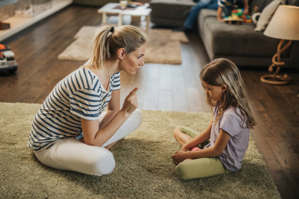 la mère gronder la petite fille sur le tapis dans le salon. - gronder photos et images de collection