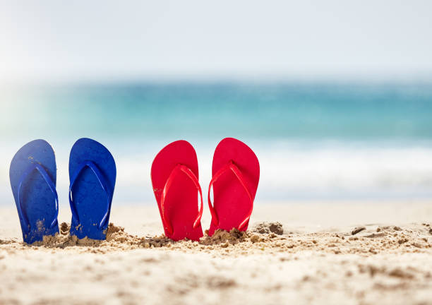 istock Two pairs of adults' beach sandals on sandy shore 958684440
