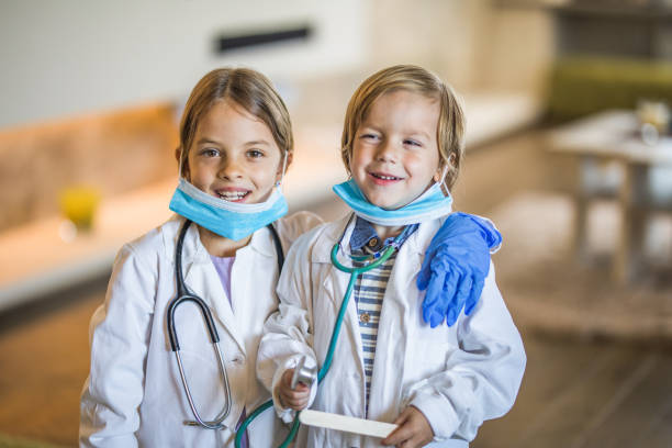 Happy little kids having fun as doctors at home.