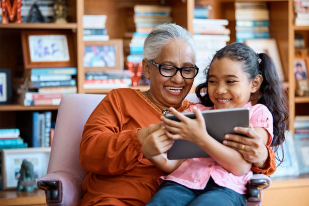 smiling females using digital tablet at home - senior adult technology child internet imagens e fotografias de stock