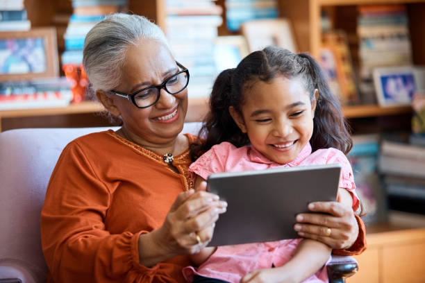 istock Happy girl with Grandmother using digital tablet 958690160