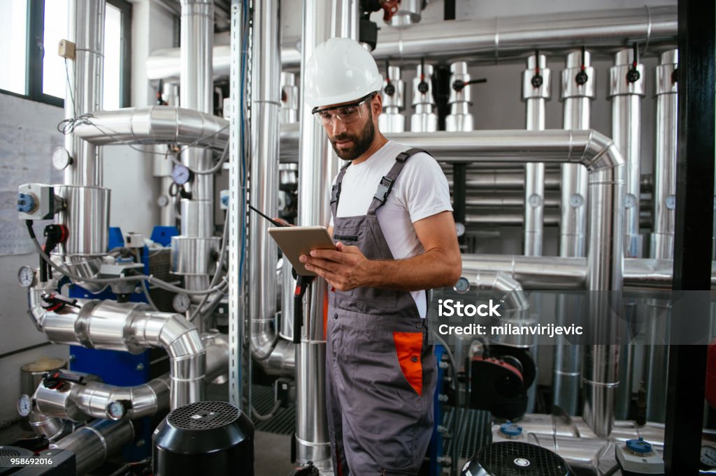 Man using tablet at Natural gas processing facility Man using tablet at Natural gas processing facility. Shallow DOF. Developed from RAW; retouched with special care and attention; Small amount of grain added for best final impression. 16 bit Adobe RGB color profile. Industry Stock Photo