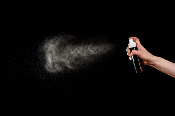 istock Atomizer in hand and cloud of small splashes isolated on black 958693104